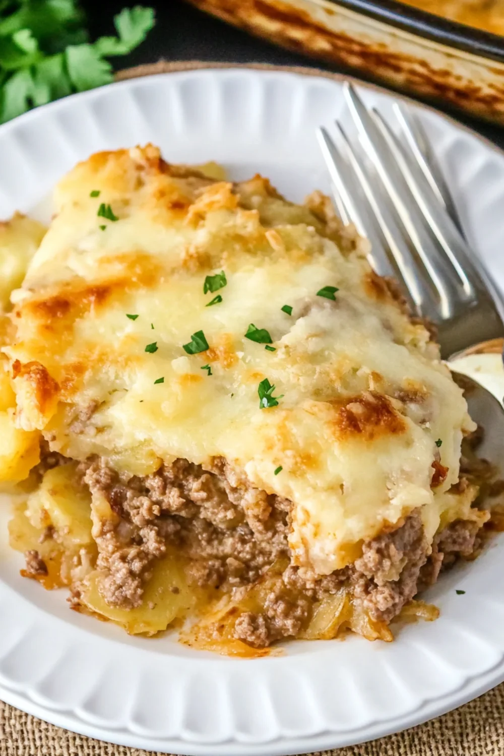 A slice of creamy and cheesy lasagna with layers of seasoned ground beef, pasta, and melted cheese, garnished with fresh parsley.