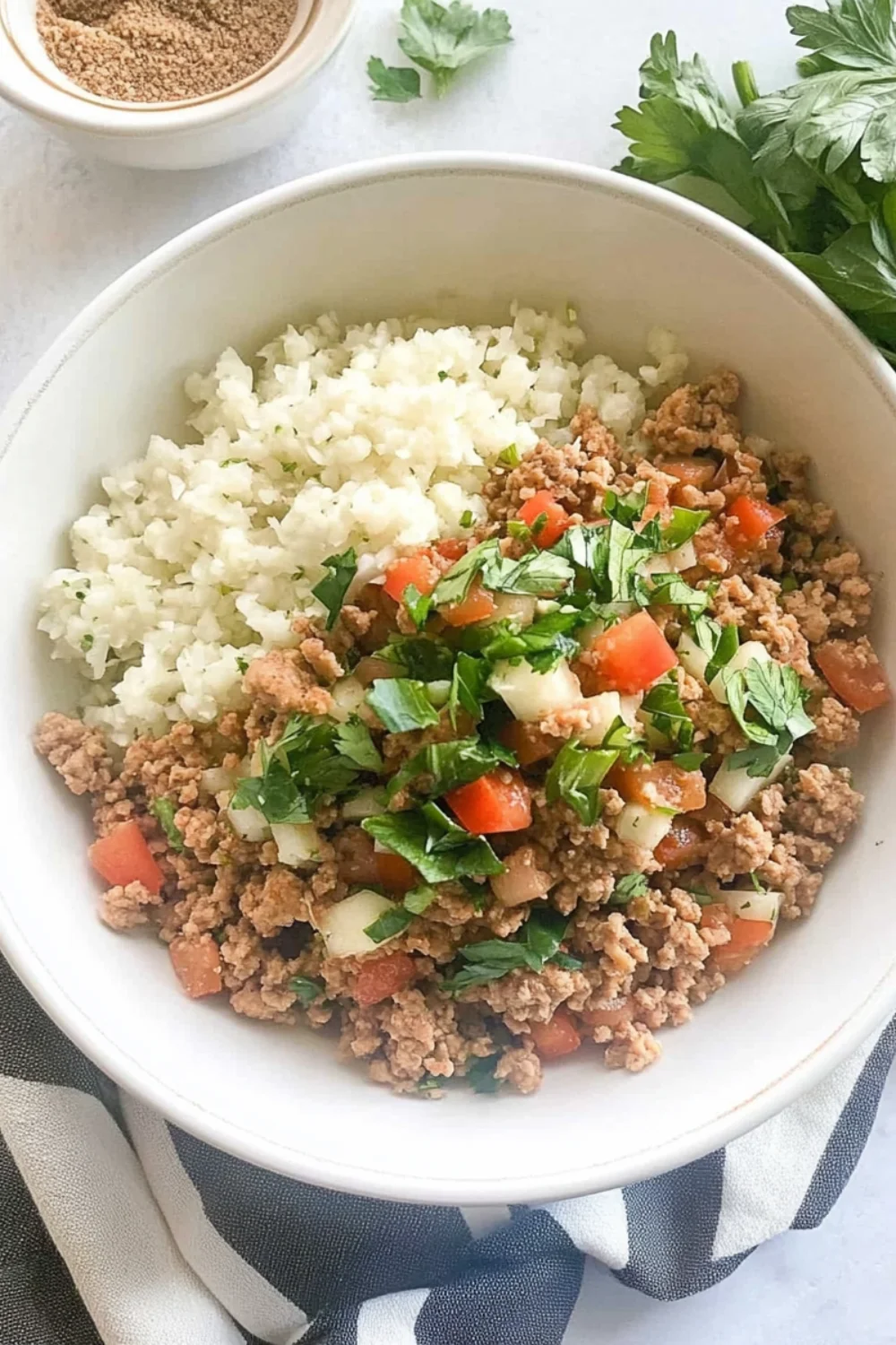 A bowl of ground turkey and cauliflower rice with fresh tomato-cucumber salsa, topped with chopped cilantro.