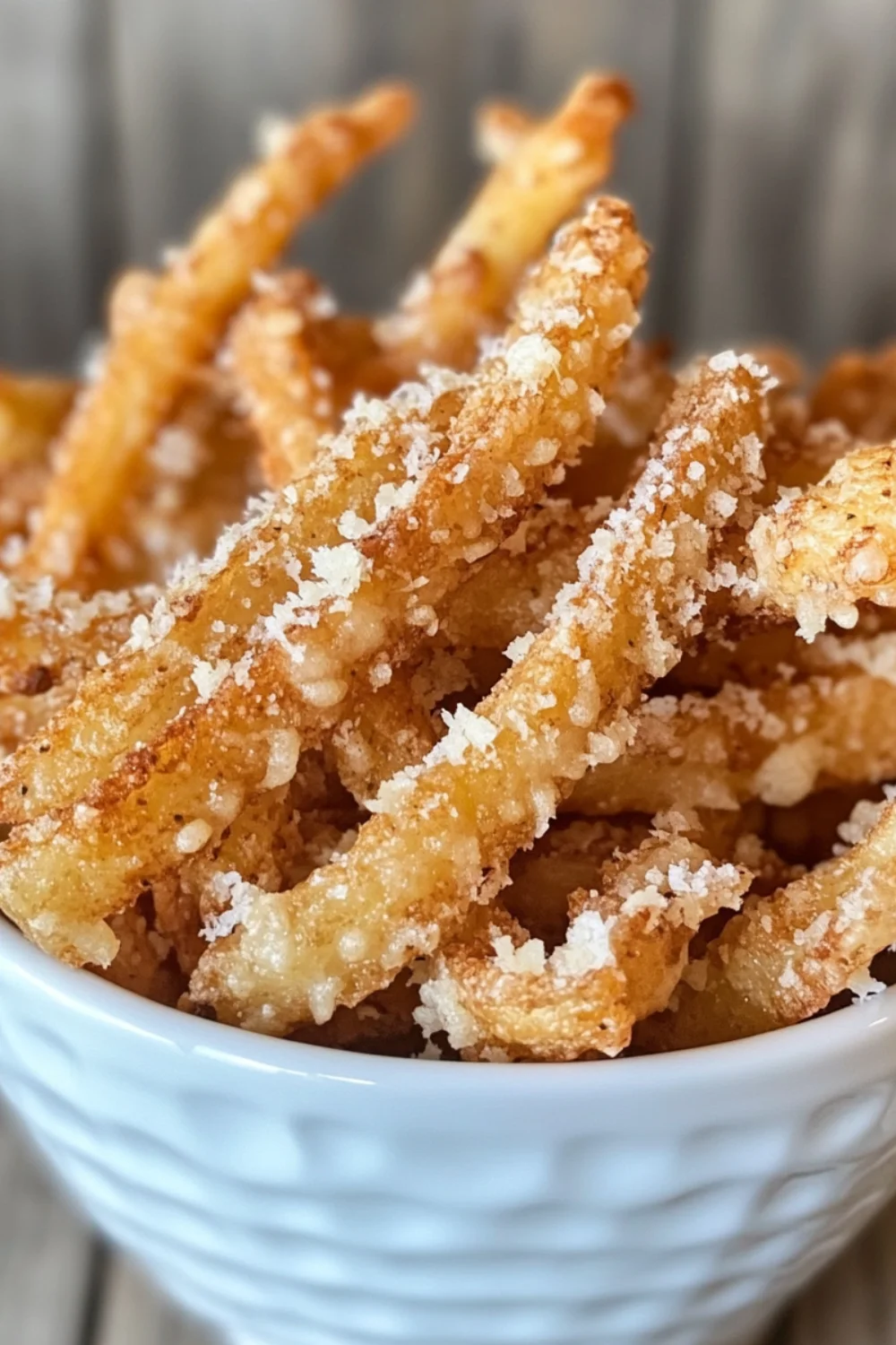 A close-up of Truffle Parmesan Fries garnished with finely grated parmesan and fresh parsley, served in a paper-lined basket.