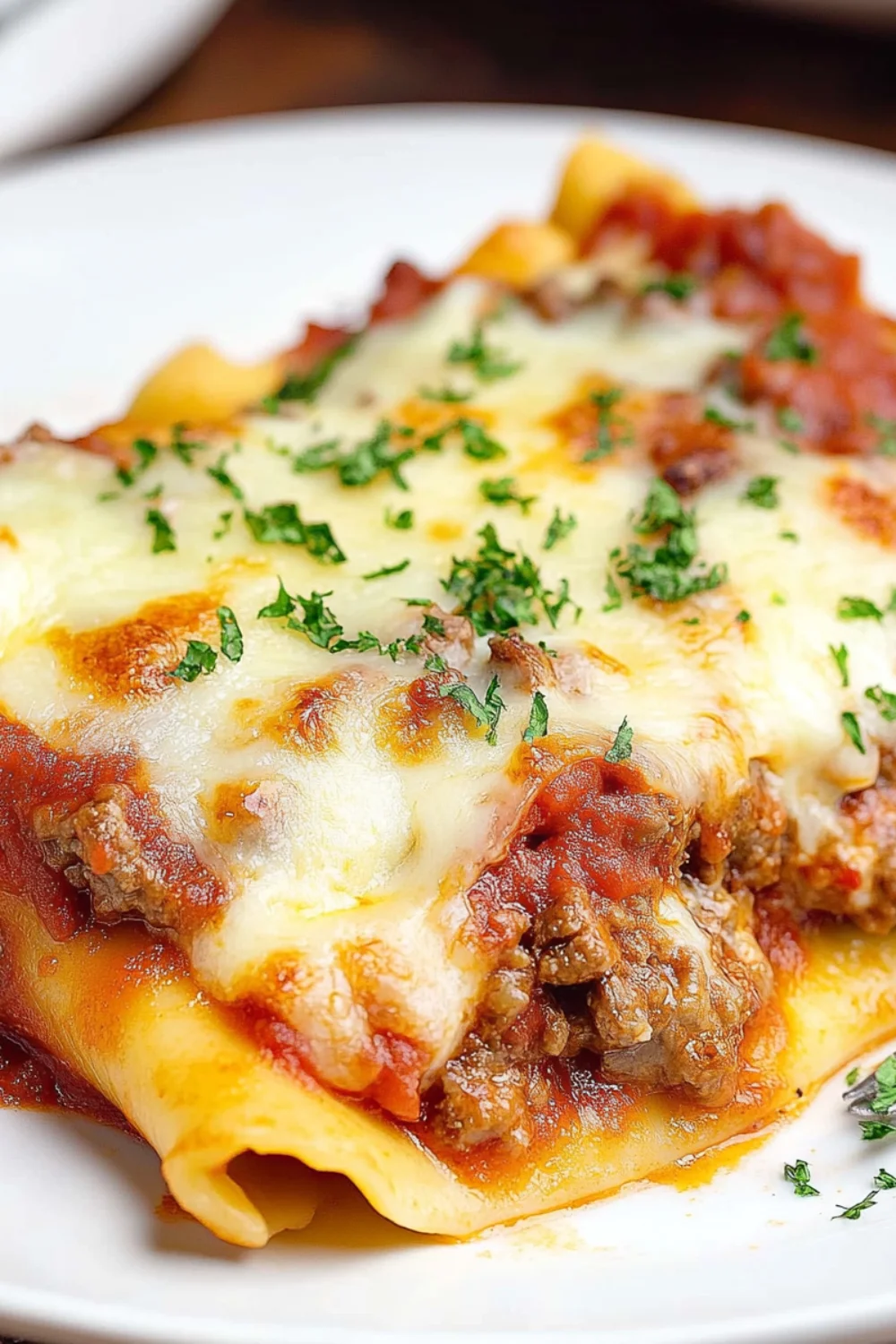 A delicious dish of stuffed manicotti pasta filled with meat and covered with mozzarella cheese, baked in marinara sauce, and garnished with fresh parsley.